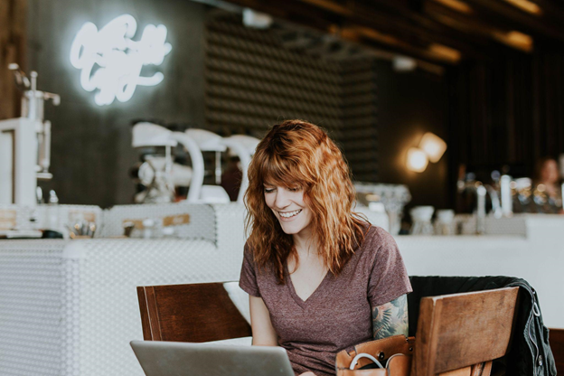 Woman smiles while learning Spanish through watching a show on her laptop