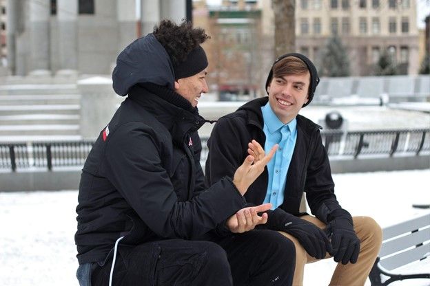 Two guys sitting on a park bench practicing Spanish conversation