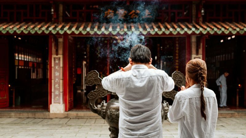 Chinese man and woman praying at the temple with burning incense-Common Mistakes In Chinese-Lingopie