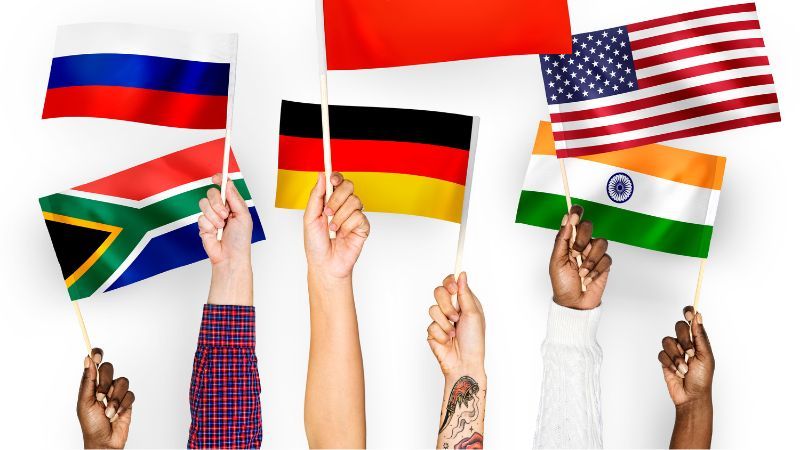 Hands with diferent skin colors holding different country flags-Start Thinking In Another Language-Lingopie 
