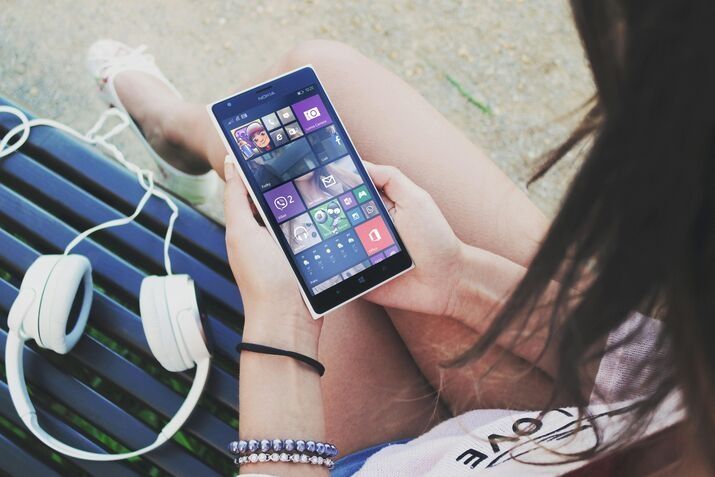 Woman holding a smart phone while sitting on a bench